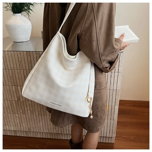 Dettaglio di una borsa tote a scacchi crema con elegante ciondolo di perle e fiori