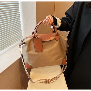 Close-up of khaki nylon tote bag with brown leather handles and geometric woven strap