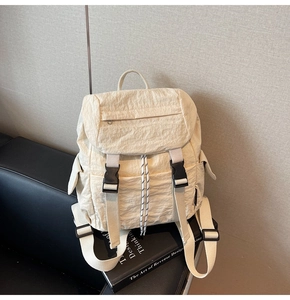 Detail of cream nylon backpack featuring crinkle texture and black buckle closure