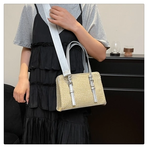 Detail of woven straw handbag with silver leather handles and adjustable nylon strap