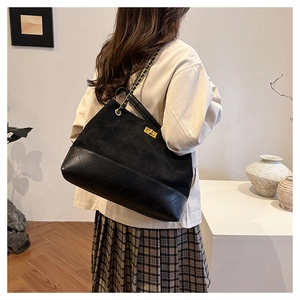 Detail of a black patchwork tote bag with suede texture and quilted leather finish