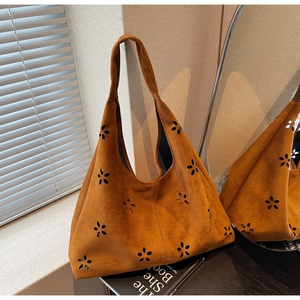 Close-up of brown suede tote bag featuring intricate laser-cut floral patterns