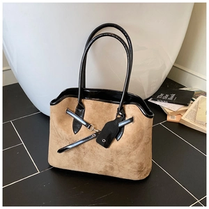 Detail of vintage brown suede tote bag with black patent leather straps in a minimal setting