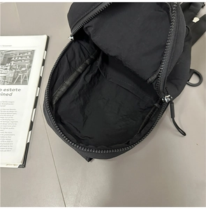 Macro view of black nylon chest bag interior with inner compartment and zipper detail