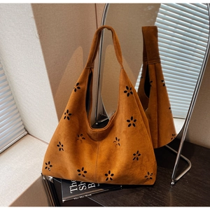 Detailed close-up of brown suede tote bag with laser-cut hollow floral pattern
