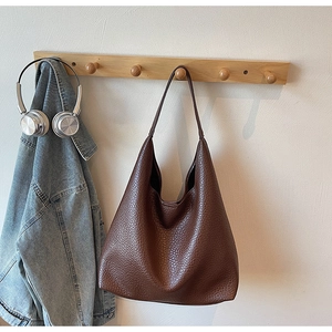 Detail of dark brown pebble leather texture on a large capacity hobo tote bag