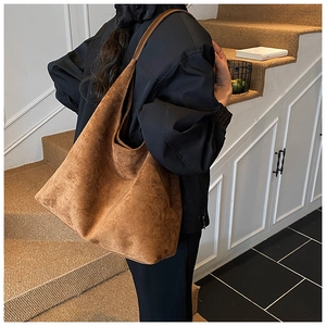 Model wearing large dark brown frosted suede tote bag showing its size and casual style