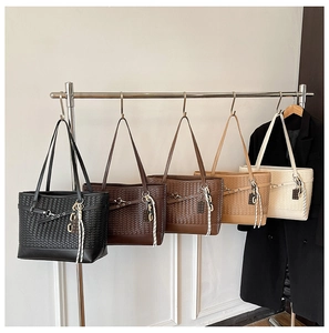 Close-up of oversized woven tote bags in five colors displayed on a metal rack