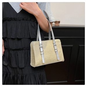 Detail of woven straw bag with silver faux leather handles and metal buckle accent
