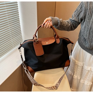 Close-up of black nylon tote bag with leather handles and patterned crossbody strap