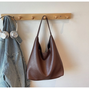 Detail of dark brown pebble leather tote bag with a spacious minimalist Hobo design