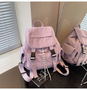 Detail of lavender nylon backpack with buckle closure and side pockets in a mirror setup