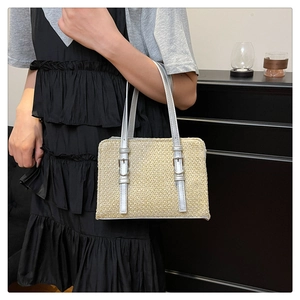Detail of straw patchwork handbag with silver straps on a black pleated dress