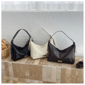 Detailed view of trio hobo bags in black, cream, and brown leather on stone steps