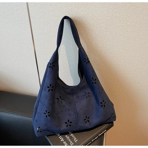 Close-up of navy blue suede tote bag with laser-cut floral patterns and matte finish
