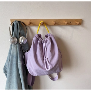 Detail of light purple nylon backpack with yellow woven handle and drawstring closure