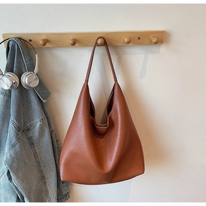 Detail of caramel orange hobo bag showing pebbled leather texture on wooden wall hook