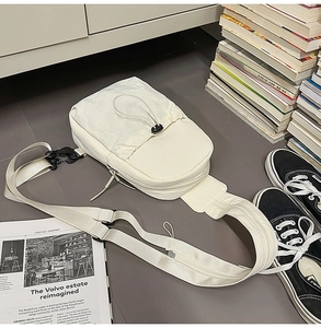 Close-up of minimalist white nylon chest bag with adjustable black drawstring and hardware