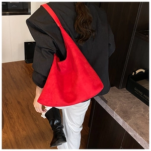 Side view of large red suede tote bag on shoulder with sleek minimalist silhouette