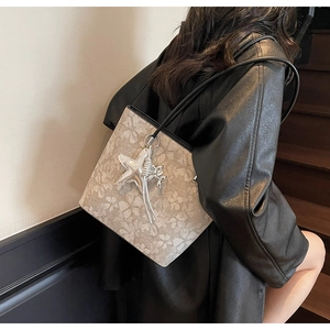 Detail of printed tote bag with floral pattern and star pendant hanging on leather strap