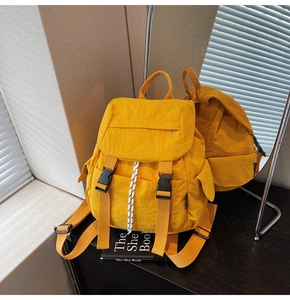 Close-up of vibrant yellow multi-pocket backpack with dual black buckles and flap cover