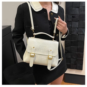 Close-up detail of white textured leather handbag with gold buckles and COIN embossing