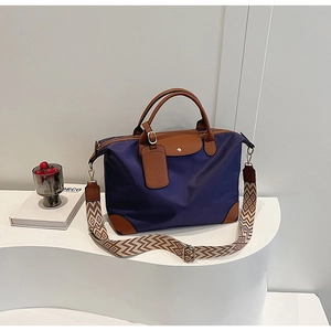 Detail of navy nylon tote bag with brown leather handles and geometric patterned strap