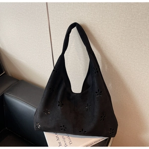 Close-up of black suede hobo bag featuring intricate hollowed-out floral patterns