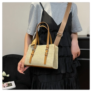 Close-up of woven straw bag featuring brown leather straps and adjustable nylon shoulder strap