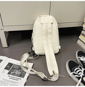 Detailed view of cream casual chest bag with wide zippered strap and wrinkled texture