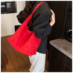 Detail of a large red matte tote bag on model showing premium suede texture and volume