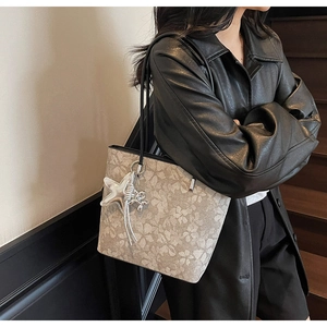 Floral print tote bag with silver star charm and tassels worn by a model in a stairwell
