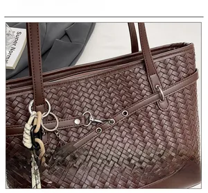 Detail shot of a dark brown woven tote bag featuring metallic rings and a chocolate tag