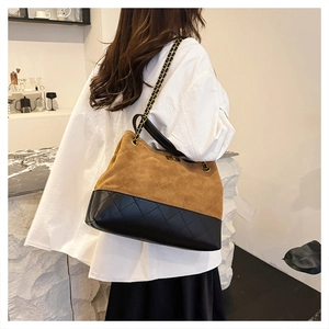 Detail of quilted tote bag with golden chain strap and mixed texture material
