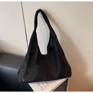 Detailed view of the black laser-cut hollow pattern on a soft suede shoulder bag