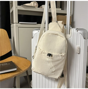 Detail of beige nylon chest bag with drawstring pocket hanging on suitcase handle