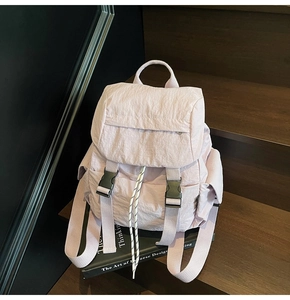 Detail of light purple nylon backpack featuring plastic buckles and drawstring accents