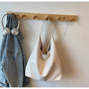 Detailed close-up of cream white pebble grain leather on a minimalist hobo tote bag