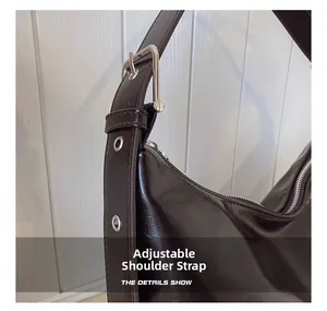 Detail of adjustable shoulder strap with silver metal buckle on a brown crescent bag