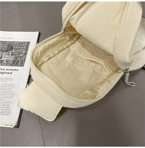 Internal view showing a cream nylon sling bag with a main pocket and inner storage slot