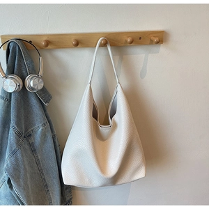 Detail of off-white tote bag showing pebbled leather texture and hobo design