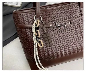 Close-up of dark brown woven leather tote bag with stylish chocolate-shaped charm detail