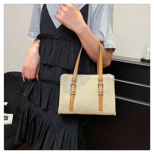 Detail of woven straw handbag with adjustable brown leather strap shown on model