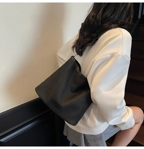Dettaglio della borsa a secchiello nera con trama a saia e patch in pelle con logo