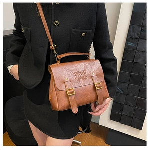 Detailed close-up of brown vintage messenger bag with fine leather texture and metal buckles