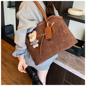 Detail of caramel suede tote bag featuring a cute plush bear charm and spacious shoulder strap