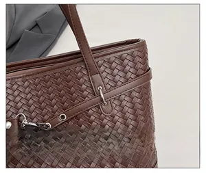Detailed view of dark brown woven leather tote with metallic buckles and rivets