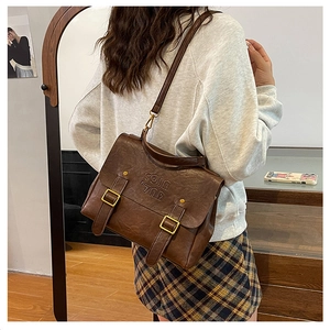 Detail view of the vintage dark brown crossbody bag with COIN 7ND embossed logo and buckles