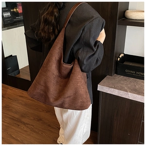 Detailed view of the dark brown matte suede texture and soft drape of this tote bag