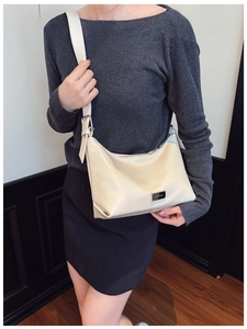 Detail of off-white leather underarm bag featuring a metallic plate and adjustable strap